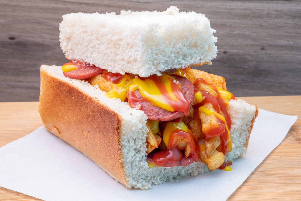 A white-bread kota-style sandwich stuffed with polony, chips, ketchup and mustard.